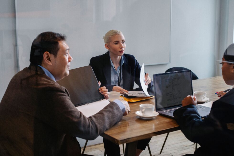 Business meeting focused on optimizing credit card processing fees, featuring a diverse team discussing strategies with laptops and documents at Optimized Payments.