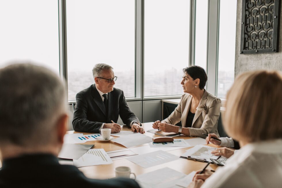 Finance team in a meeting at Optimized Payments, discussing strategies to reduce credit card processing fees, with charts and documents on the table, enhancing payment efficiency.