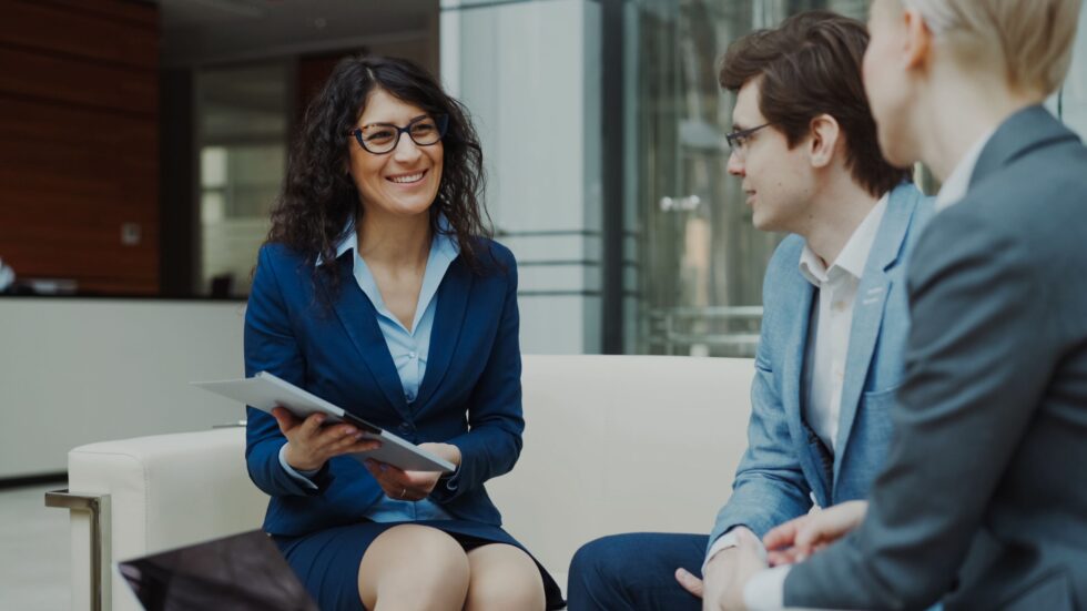 Business team discussing credit card processing fees optimization with Optimized Payments consultant in a modern office setting.